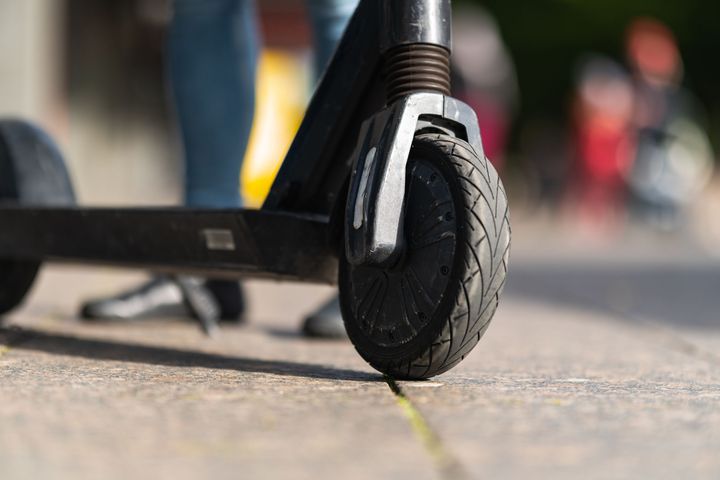 Närbild på framhjulet av en elskoter på en trottoar.