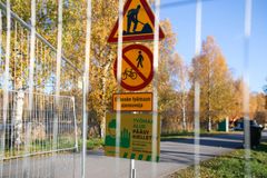 Skyltar vid byggarbetsplats med varningar och restriktioner, omgiven av höstlöv.