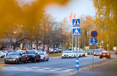 Katu, jossa on pysäköityjä autoja ja liikennemerkkejä.