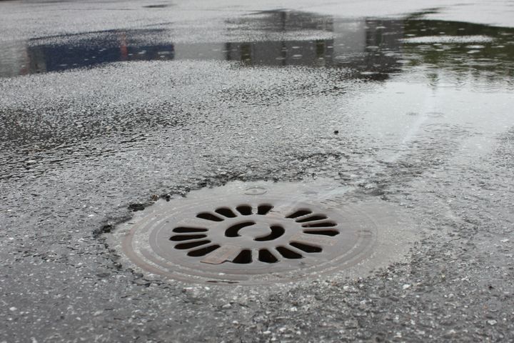 Katuviemäri märällä asfaltilla sateen jälkeen.