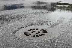 Bild på en regnvåt gata med en brunnslock centralt placerad.