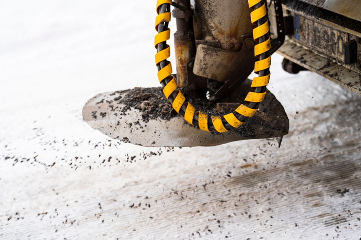 Sandningsmaskin som sprider sand på en snötäckt väg.