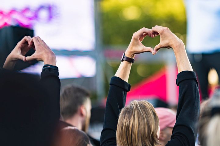 Personer i en publik formar hjärtan med sina händer ovanför huvudet.