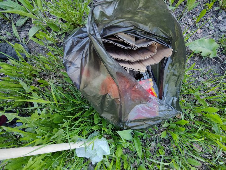 Nurmikolla musta jätesäkki, jossa on roskia.