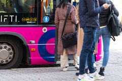Ihmisiä nousemassa vaaleanpunaiseen bussiin.