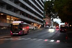 Stadsgata i skymningen med Liftis buss; människor väntar på trottoaren.