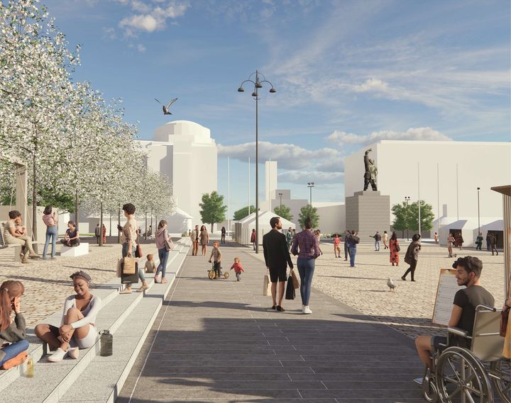 Gatuliv med människor som promenerar och sitter. Träd i blom, staty i bakgrunden.