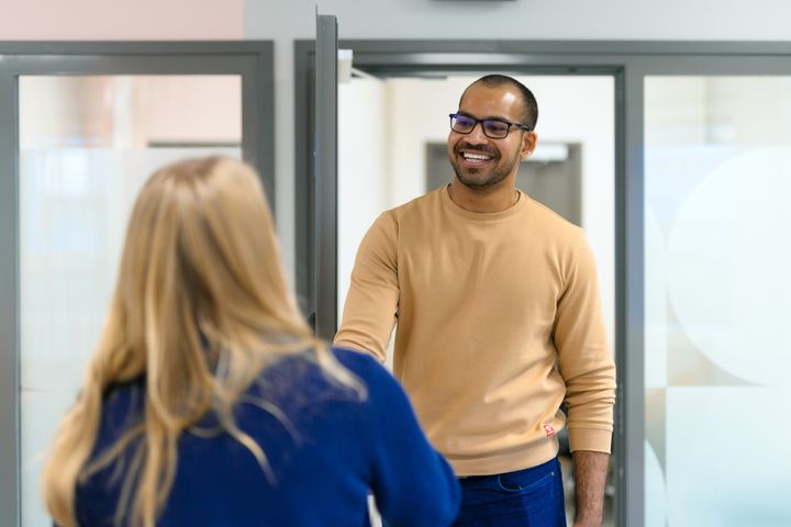Två personer hälsar på varandra genom ett handslag i ett kontor.