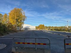 Tyhjä pysäköintialue syksyisten puiden ja sinisen taivaan alla.