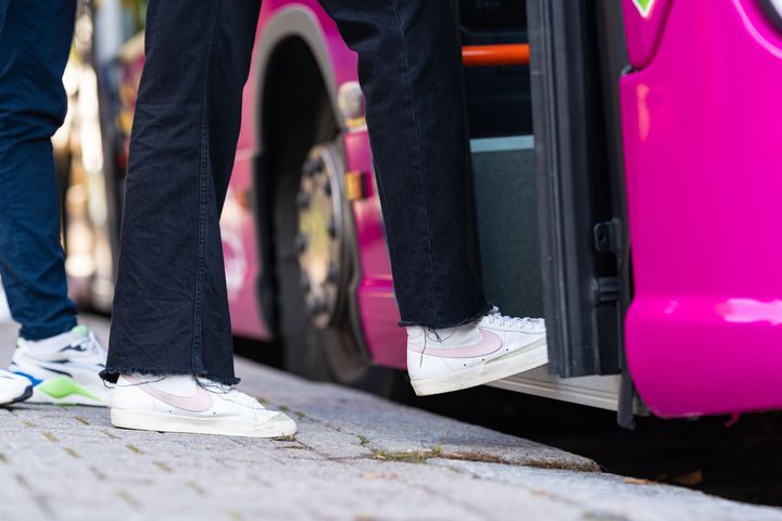 Person stiger på en rosa stadsbuss.