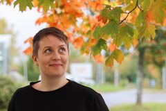 Erityisopettaja hymyilee kuvassa, taustalla ruskanvärisiä vaahteran lehtiä.