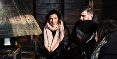 A group of people sitting together, wearing winter clothing, inside a wooden structure.