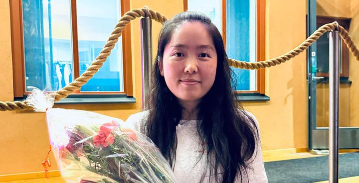 A person standing indoors holding a bouquet of flowers.