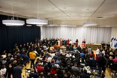 A large group of people seated and standing in VAMK's festival hall with some individuals on a stage at the front.