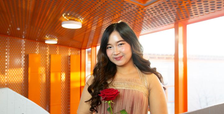 A girl with a rose in front of a window at VAMK.