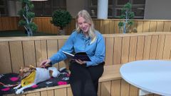 Kuvassa opiskelija istuu penkillä ja silittää lukukoiraa, joka makaa hänen vieressään.