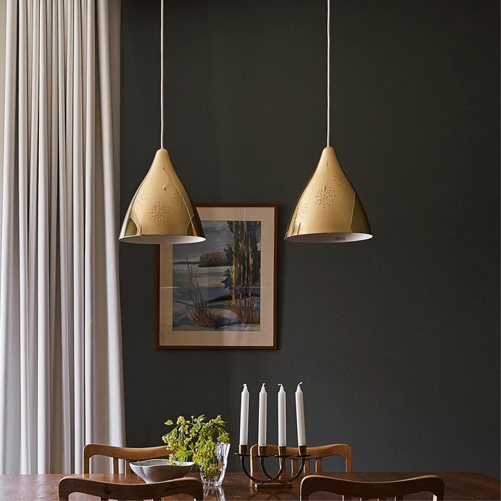 Kaksi riippuvalaisinta ruokapöydän yläpuolella, taustalla tumma seinä
