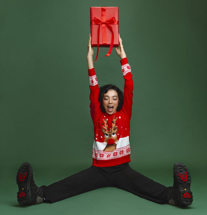 Hyväntuulinen nainen istuu ja kannattelee käsissään joulupakettia