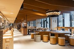 Avara ja moderni ravintolatila, jossa on puupintaisia kalusteita ja suuri, pyöreä pöytä keskellä.