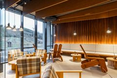 Valoisa ravintolatila, jossa on puisia tuoleja ja pöytiä sekä suuret ikkunat, joista näkyy laskettelurinteitä.