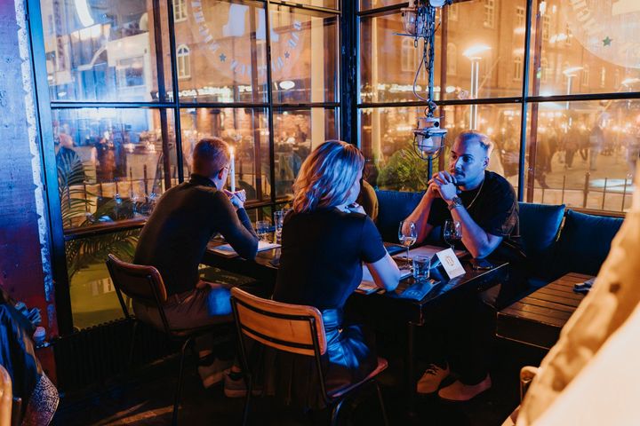 Neljä henkilöä istuu ravintolassa pöydän ympärillä nauttien juhlatunnelmasta.