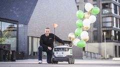 Mies kyykistyy robottikuljetuslaitteen viereen, johon on kiinnitetty ilmapalloja.