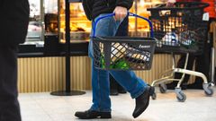 Henkilö kantaa ostoskoria ruokakaupassa.