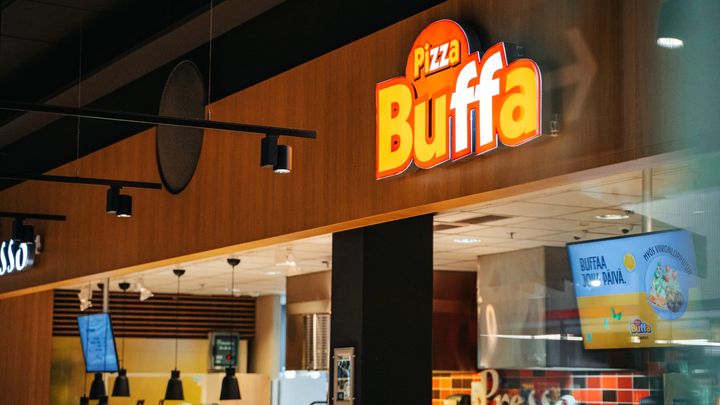 Alt-teksti: Ravintolan Pizza Buffa kyltti sisätiloissa, taustalla ruokailutiloja.