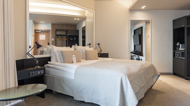 Kuva uudistetusta hotellihuoneesta, Supreme Solo Sauna -luokassa. Huoneessa on moderni sisustus, leveä sänky, vaalea värimaailma ja sauna.