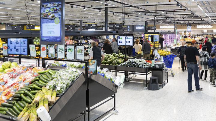S-marketin myymälätila, jossa asiakkaita ja vihannesosastoja.