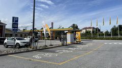 Latausasema Viitasaarella, jossa on useita sähköautojen latauspisteitä ja keltaisia banderolleja.