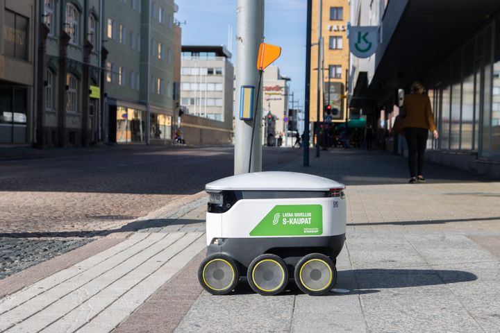 Itseohjautuva kuljetusrobotti kulkee jalkakäytävällä kaupunkiympäristössä.