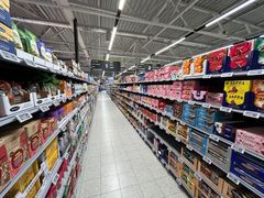 Elintarvikkeiden käytävä supermarketissa, hyllyillä erilaisia tuotteita molemmilla puolilla.