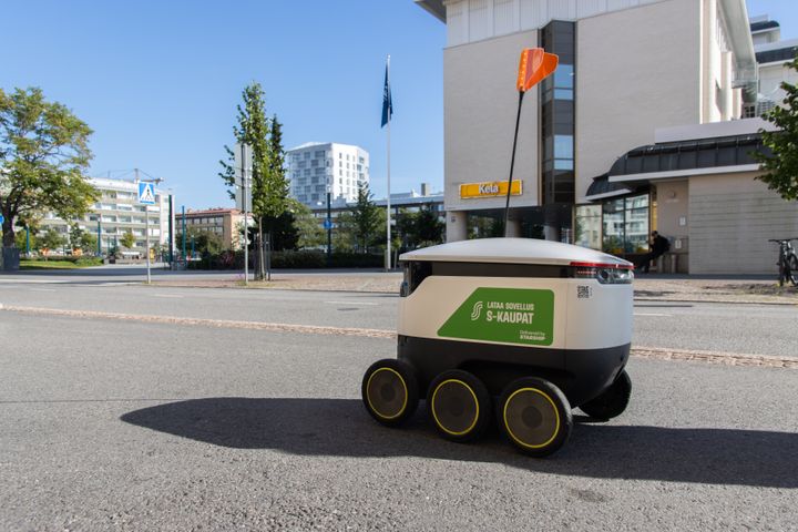 Pieni robottikuljetin liikkuu jalkakäytävällä kirkkaana päivänä.