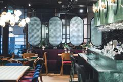 Moderni ravintola, jossa on tyylikkäitä valaistuksia, puisia tuoleja ja värikkäitä yksityiskohtia.