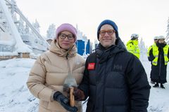 Kaksi ihmistä talvivaatteissa pitelee yhdessä muurauskauhaa lumisessa maisemassa.