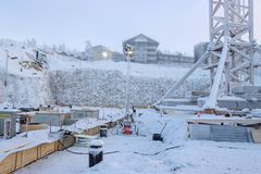 Talvinen rakennustyömaa, jossa paljon lunta. Taustalla taloja ja suuri nosturi.