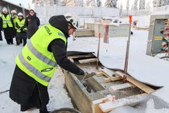 Henkilö valaa lieriön muotoista esinettä betonilaattaan talvisissa olosuhteissa.