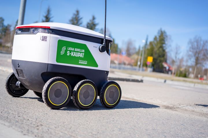 Alt-teksti: Pieni kuljetusrobotti liikkuu katua pitkin auringonpaisteessa.