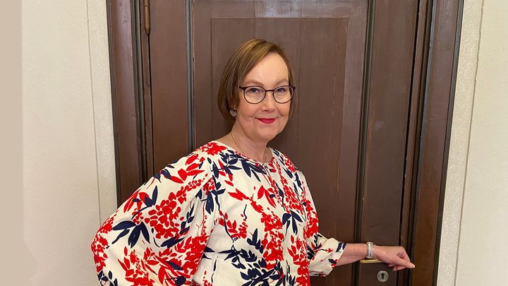 Kuvassa tumma hymyilevä nainen, Nyyti ry:n toiminnanjohtaja Minna Savolainen,  mielenterveyden edistämisen periaatepäätöksen työryhmän tuore puheenjohtaja.