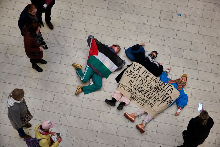 Ihmisiä makaa selällään maassa, yhdellä päällään Palestiinan lippu ja kahdella muulla mielenosoituslakana.