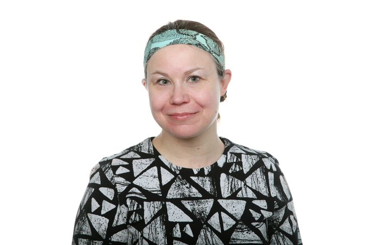 A woman with a patterned headband and a geometric top against a white background.