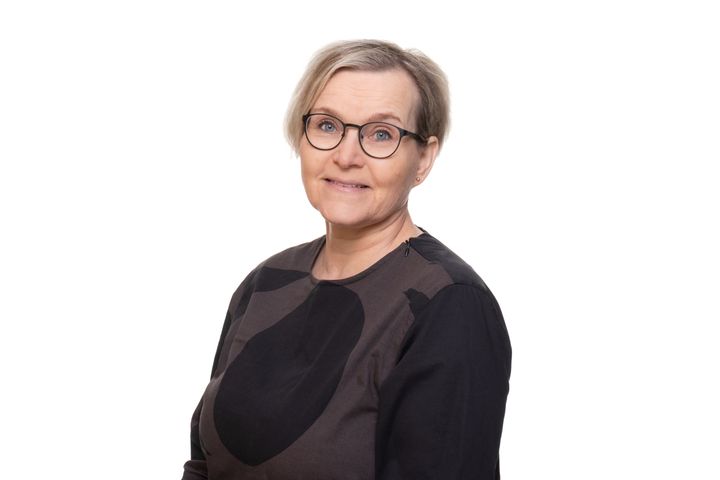 Nainen, jolla on lyhyt vaalea tukka ja silmälasit, hymyilee mustassa paidassa.
