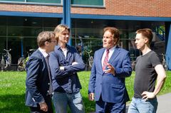 Neljä henkilö keskustelemassa ulkona yliopiston rakennuksen edustalla.