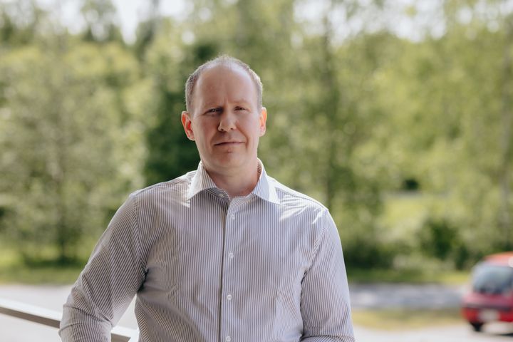 Kuvassa on Jari Luomala, joka seisoo ulkona; taustalla näkyy vehreitä puita.
