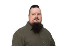 Henkilö studiokuvassa. Tummanvihreä kaulupaista ja parta.