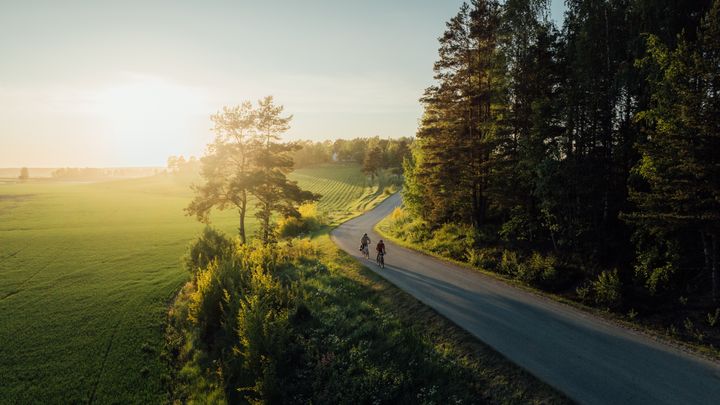 Pyöräilijät maaseutumaisemisssa.