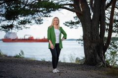 Shqipe Buzuku meren rannalla, taustalla näkyy rahtialus
