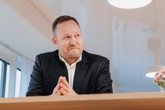 Antti Kupulainen kuvattuna etualaviistosta. Hän nojaa korkeaan pöytään, katse on vasemmalle. Taustalla vaaleaa toimistotilaa.