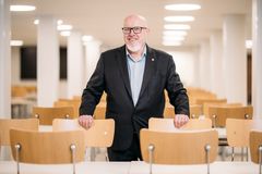 Munkkiniemen yhteiskoulun rehtori Aki Holopainen koulun ruokalassa kunnostettujen tuolien kanssa